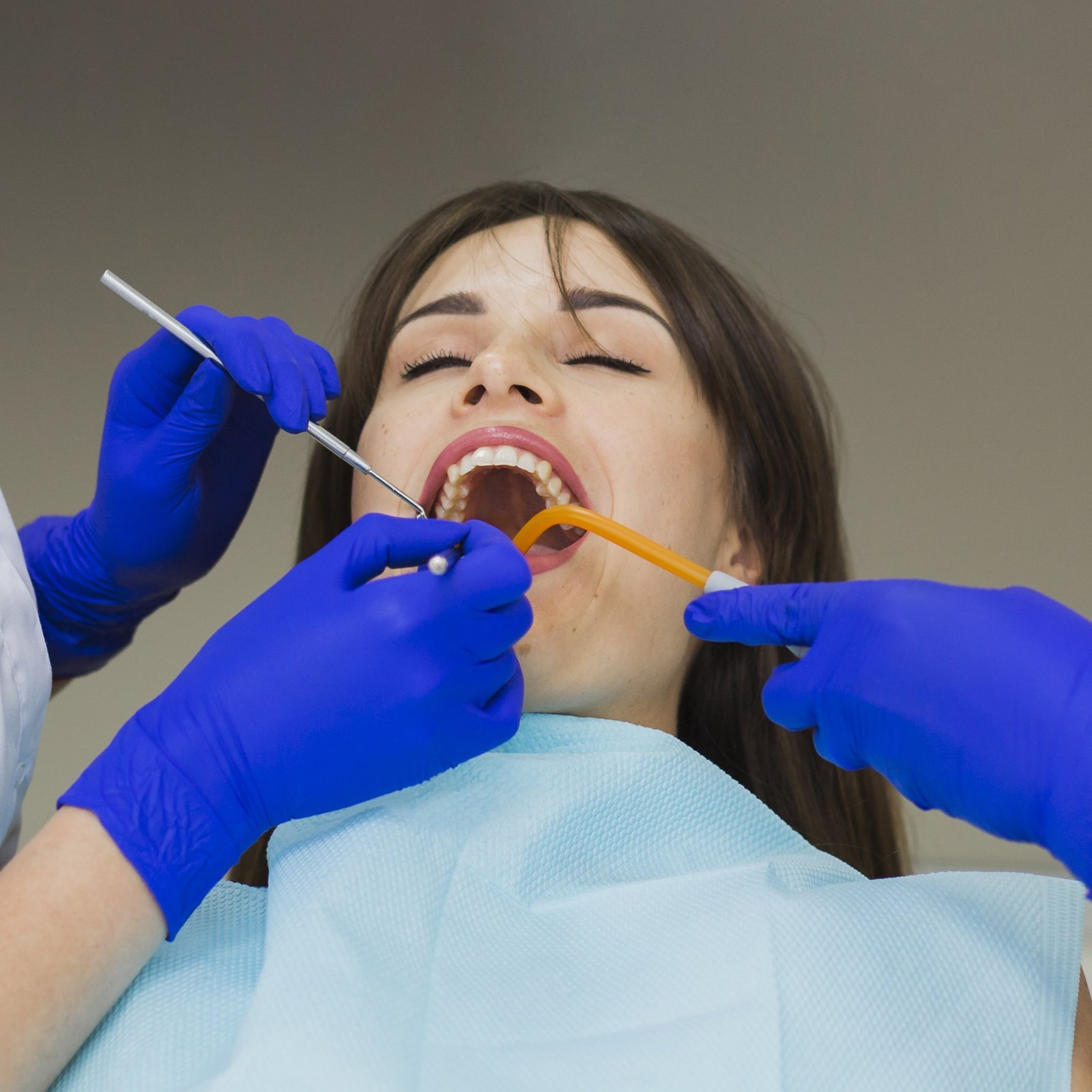 woman-getting-her-teeth-checked-by-dentists-min
